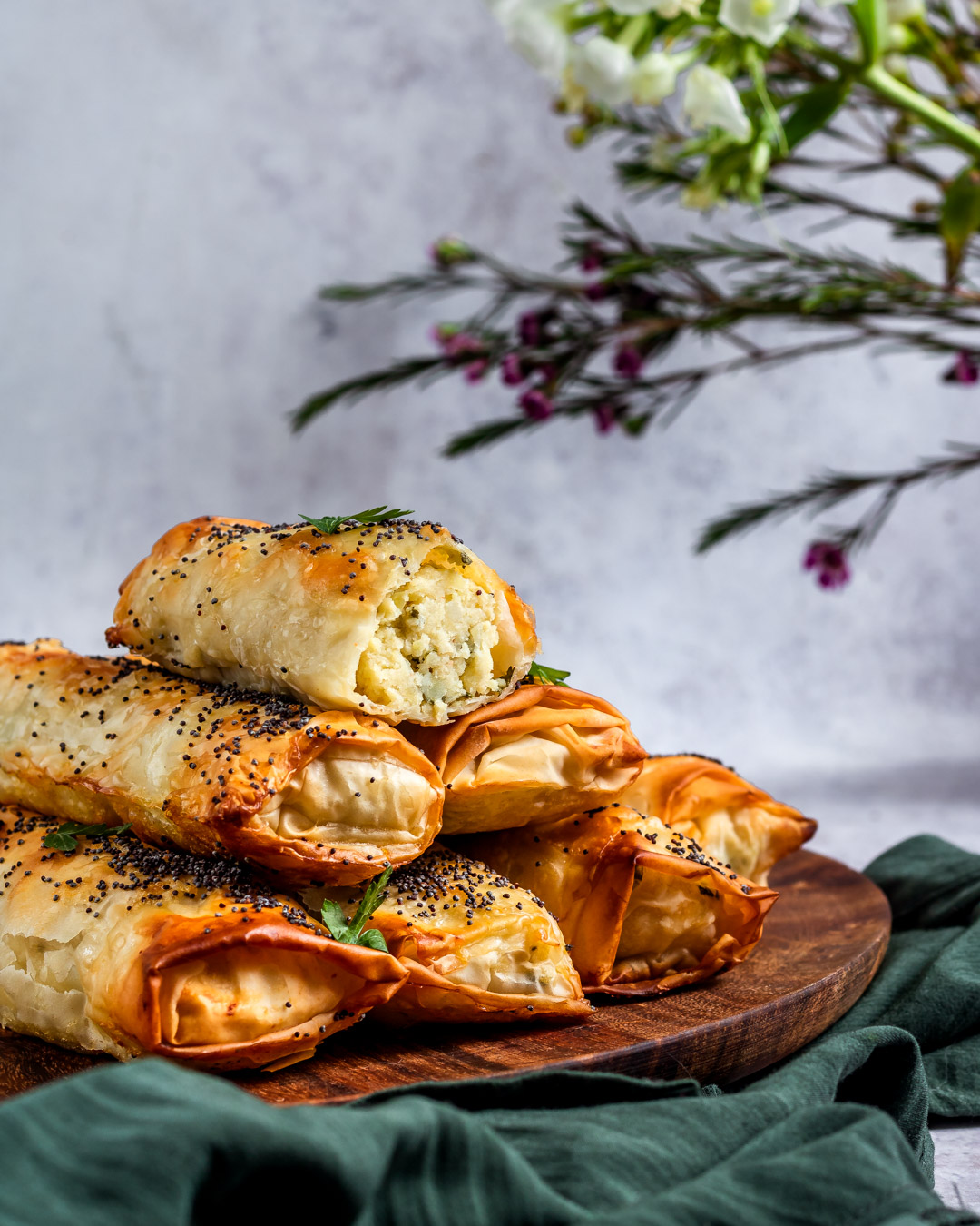 Golden, flaky börek pastries arranged on a rustic wooden board, steam rising gently to suggest freshness